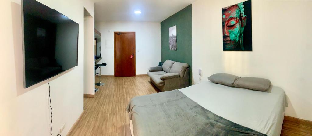 a bedroom with a bed and a couch and a television at Flat Belvedere com piscina in São Vicente