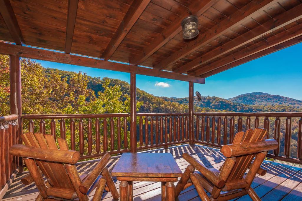 um alpendre com 2 cadeiras e uma mesa num deque em Brown Bear Lodge -4 Bed, 4 Bath huge Gameroom and mountain views em Sevierville