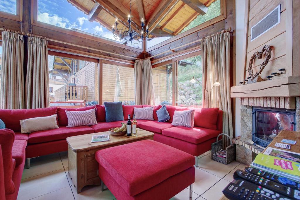 a living room with a red couch and a fireplace at Chalet Madeleine in Morzine