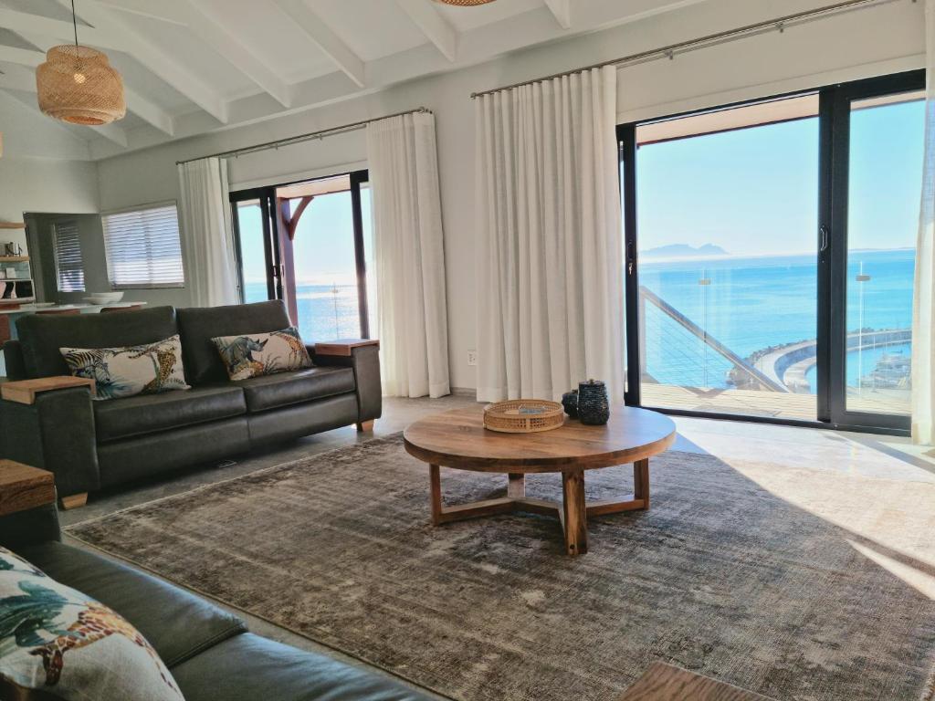 uma sala de estar com um sofá e uma mesa de centro em The Anchor, Luxury living for 2 with sea view and Jacuzzi em Gordonʼs Bay