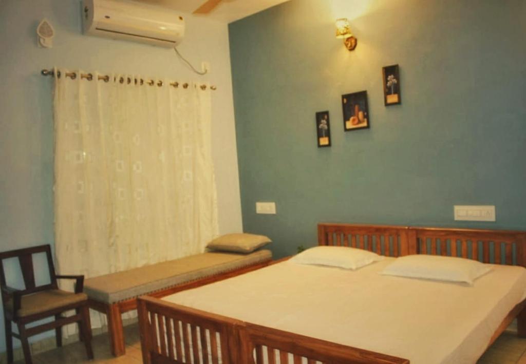 a bedroom with two beds and a chair and a window at High Island Homestay in Cochin