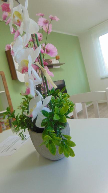 wazon wypełniony różowo-białymi kwiatami na stole w obiekcie Ferienwohnung August 18 w mieście Gelenau