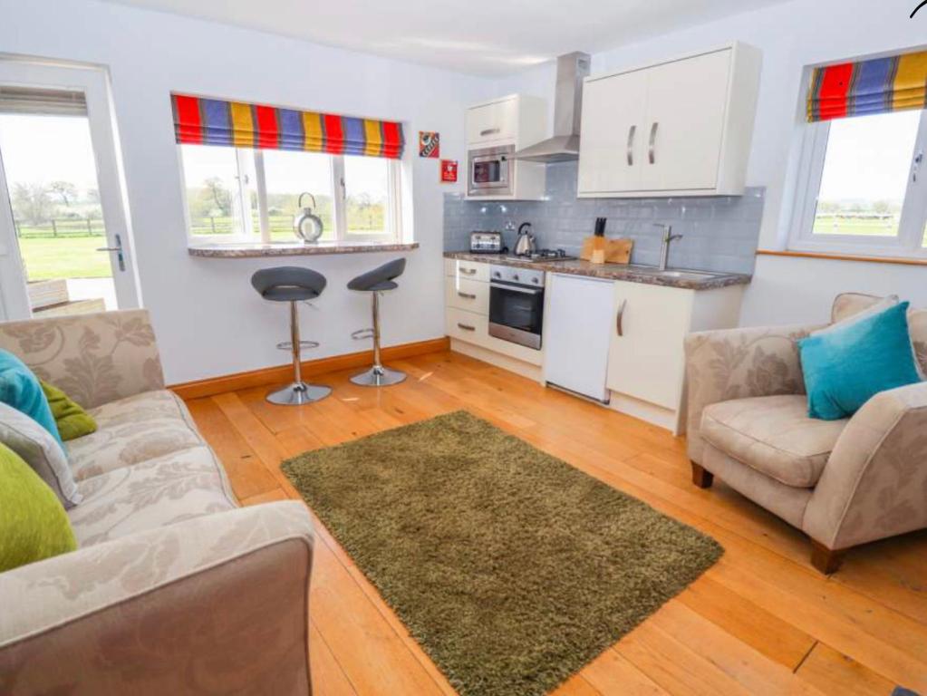 a living room with a couch and a kitchen at Meadow View at Keepers Cottage in Eaton