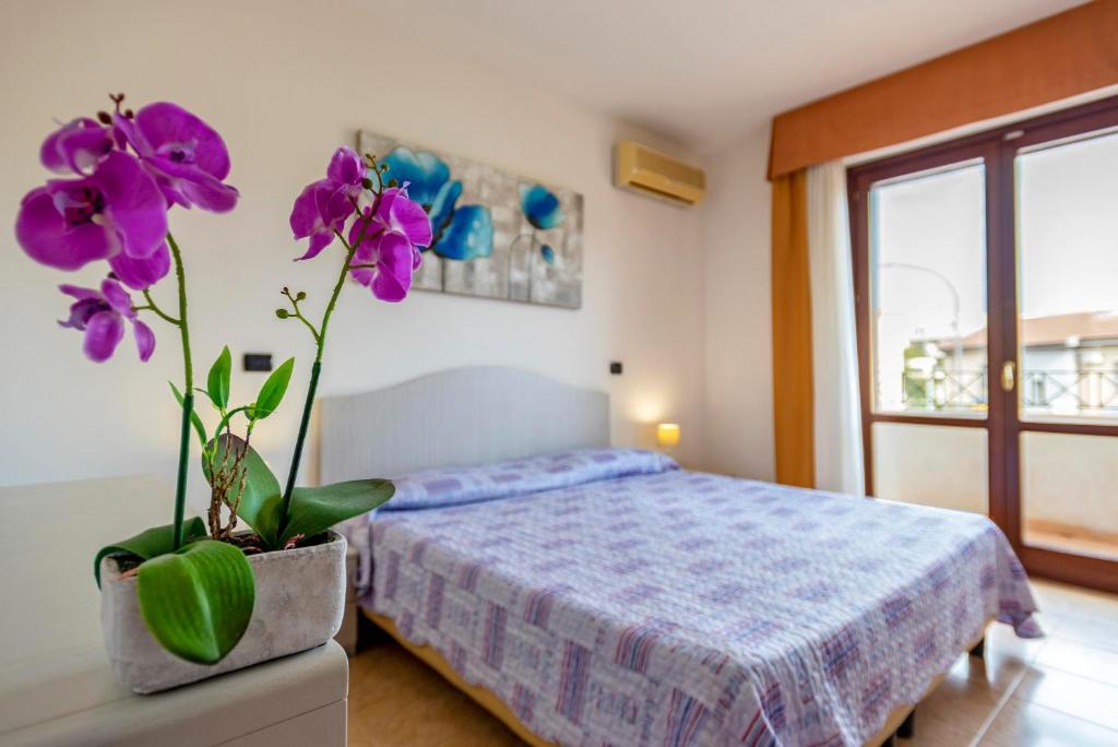 sypialnia z łóżkiem i wazonem z fioletowymi kwiatami w obiekcie Egeo apartment w mieście Alghero