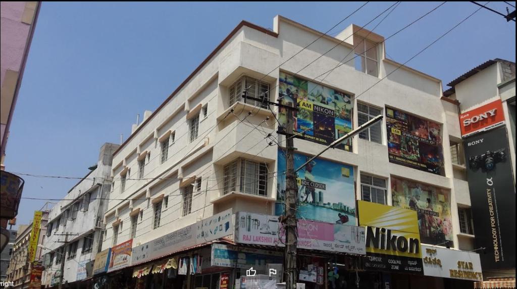 un edificio blanco alto con anuncios en el costado en Star Residency, en Mysore