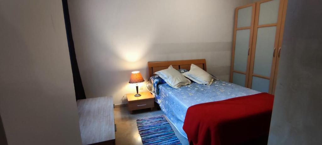ein Schlafzimmer mit einem Bett und einer Lampe auf einem Nachttisch in der Unterkunft Apartamentos Serrallo, Parking gratuito y cocina, Alhambra y playa in Granada