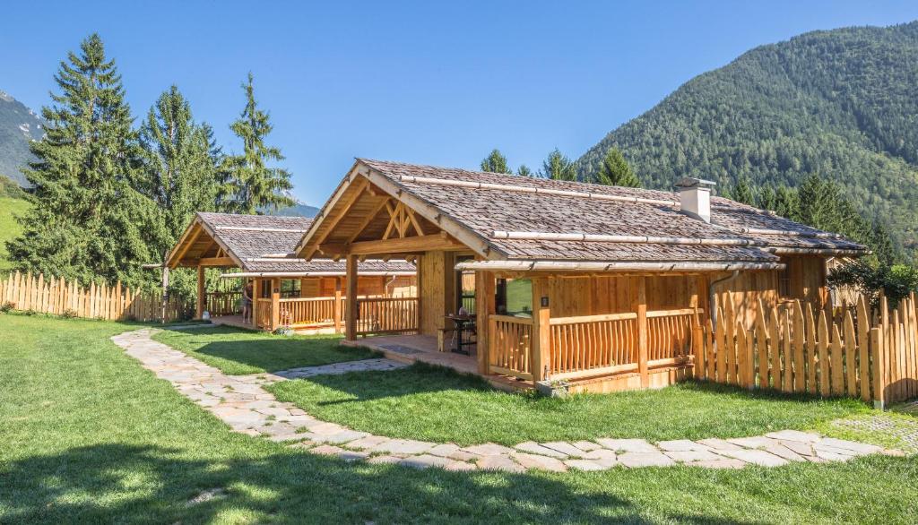 a wooden cabin with a fence and mountains in the background at Ledro Mountain Chalet in Ledro
