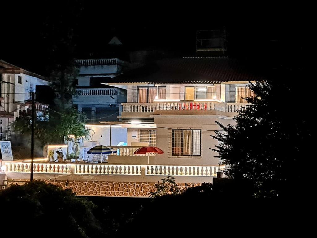Un grand bâtiment blanc avec balcon est disponible la nuit. dans l'établissement Fogg Villa - Valley View / Swimming pool / AC, à Mahabaleshwar