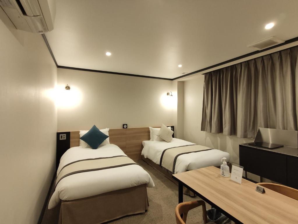 Habitación de hotel con 2 camas y mesa en yksi SAUNA & STAY en Tokio