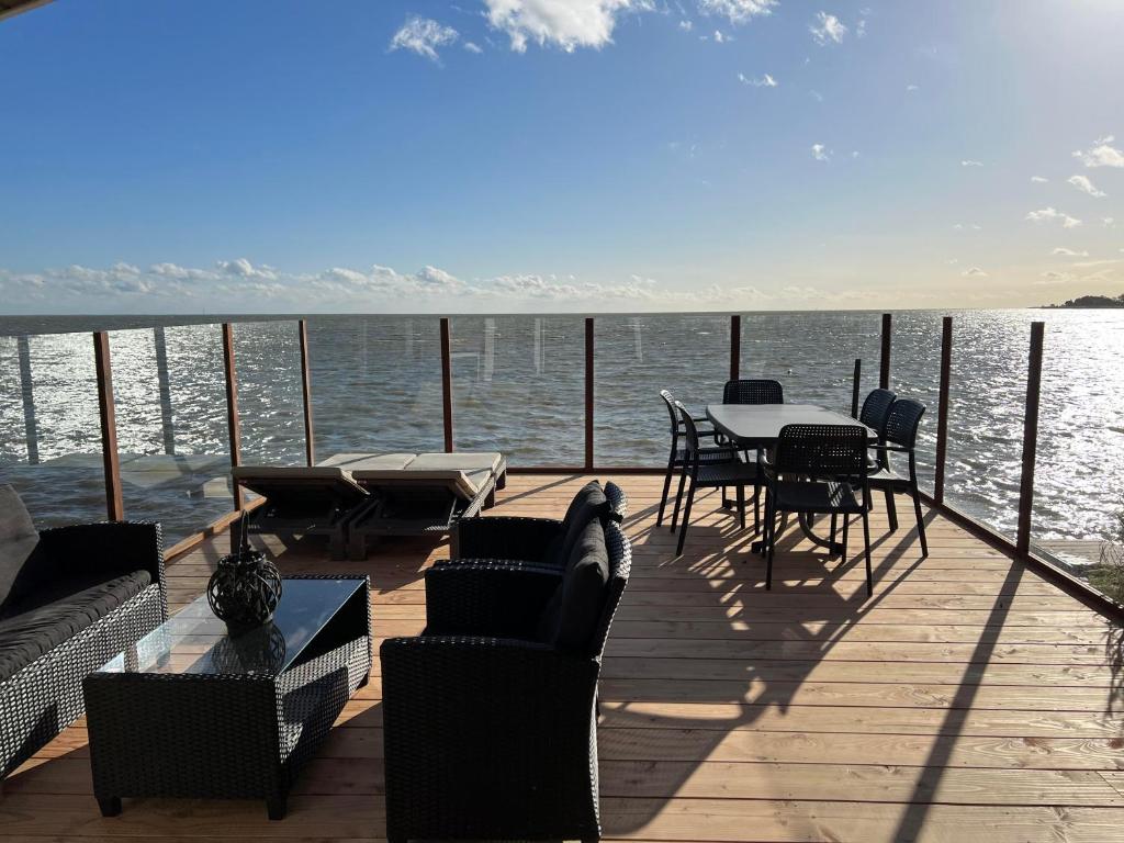 a deck with a table and chairs on the water at Exclusieve vakantievilla ***** Markermeer in Bovenkarspel