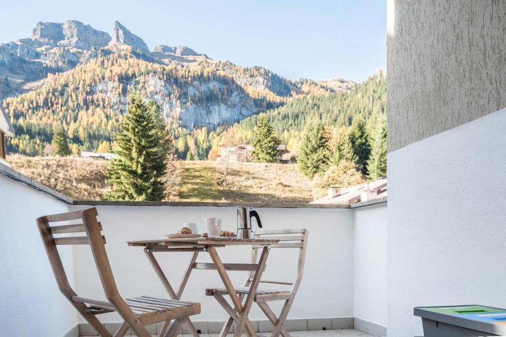 een tafel en stoelen op een balkon met uitzicht op de bergen bij Casa Muffolina in Canazei