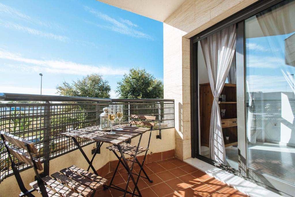 un balcón con una mesa con gafas. en Apartamento Mairena, en Mairena del Aljarafe