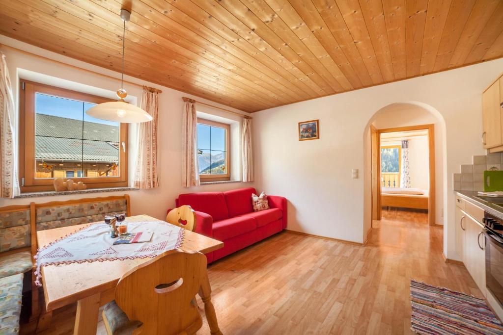 a living room with a red couch and a table at Egarthof Ferienwohnung Alpenrose in Moso