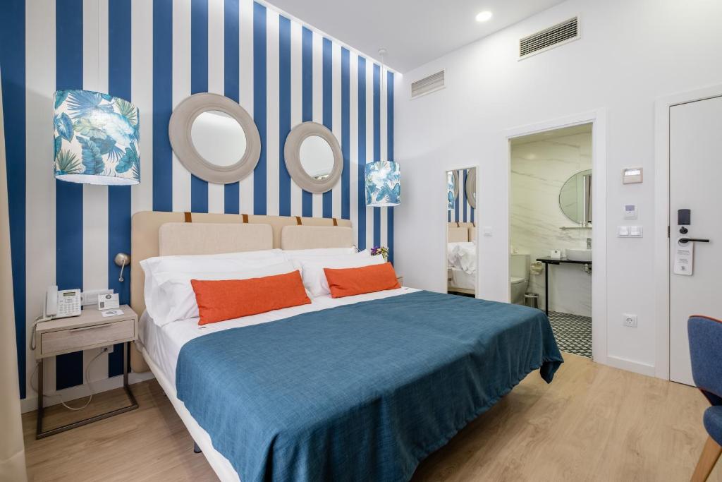 a bedroom with a bed with blue and white stripes at Soho Boutique Urban in Málaga