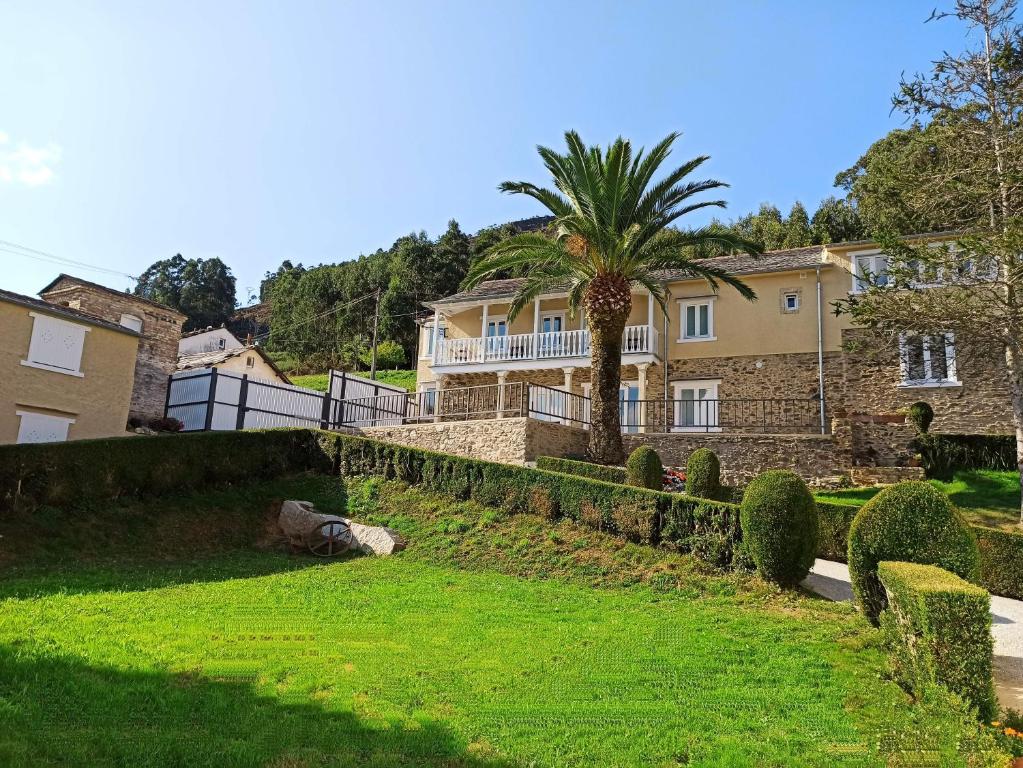 una casa con una palmera frente a un patio en Apartamentos Minas de Silvarosa, en Viveiro