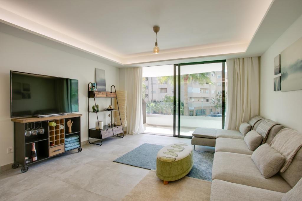 sala de estar con sofá y TV en Apartamento Sadio - Residencial Infinity en Estepona