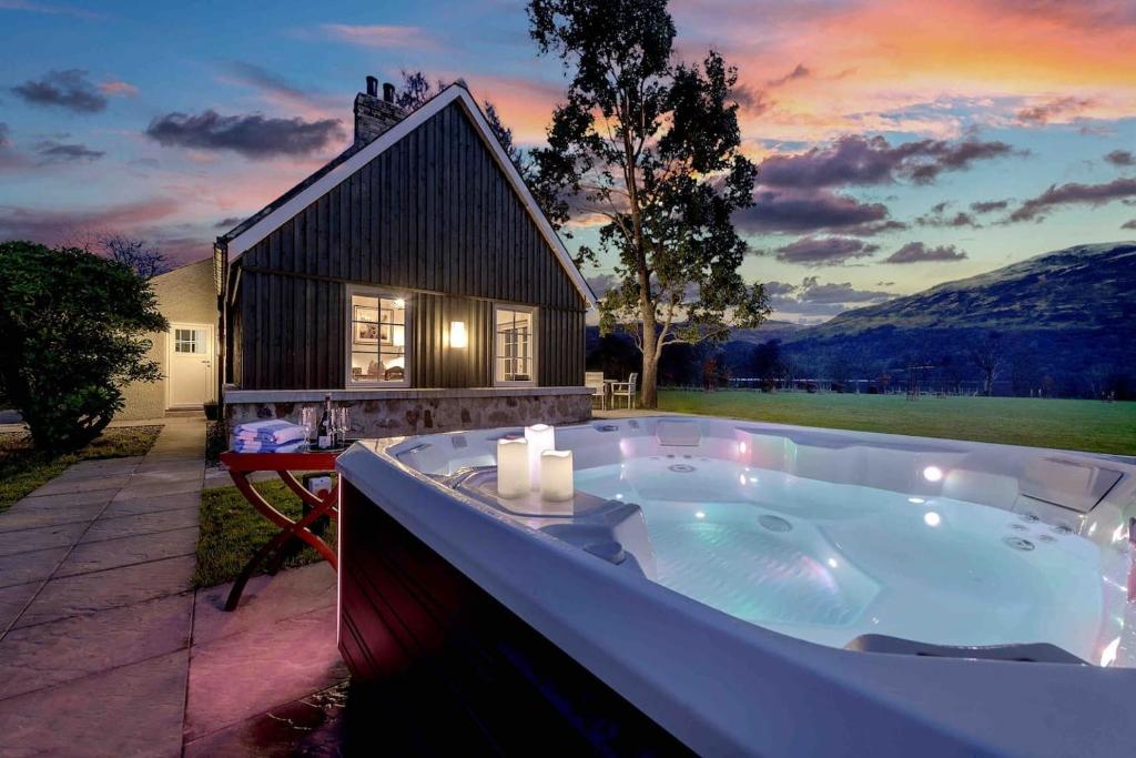a jacuzzi tub in front of a house at Dalveich Cottage w hot tub & stunning views in Lochearnhead