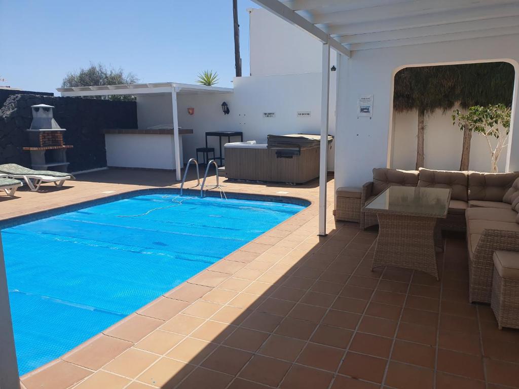 a swimming pool in the middle of a patio at FUN FAMILY VILLA-CRAZY GOLF COURSE-HEATED POOL-COCKTAIL BAR-JACUZZI-GAMES ROOM-WIFI &UK TV in Puerto del Carmen