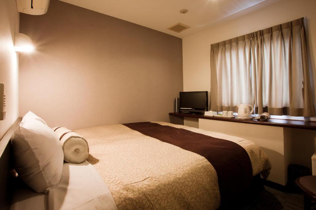 um quarto de hotel com uma cama e uma janela em Kakegawa Station Hotel em Kakegawa