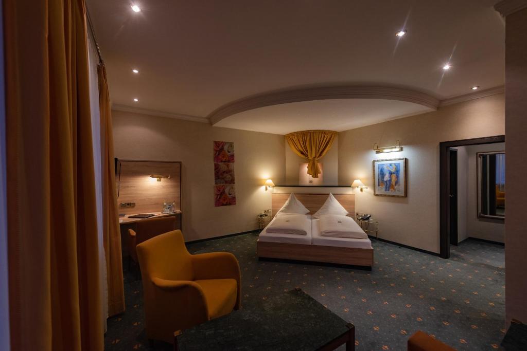 Habitación de hotel con cama y silla en Hotel am Schloss, en Illertissen