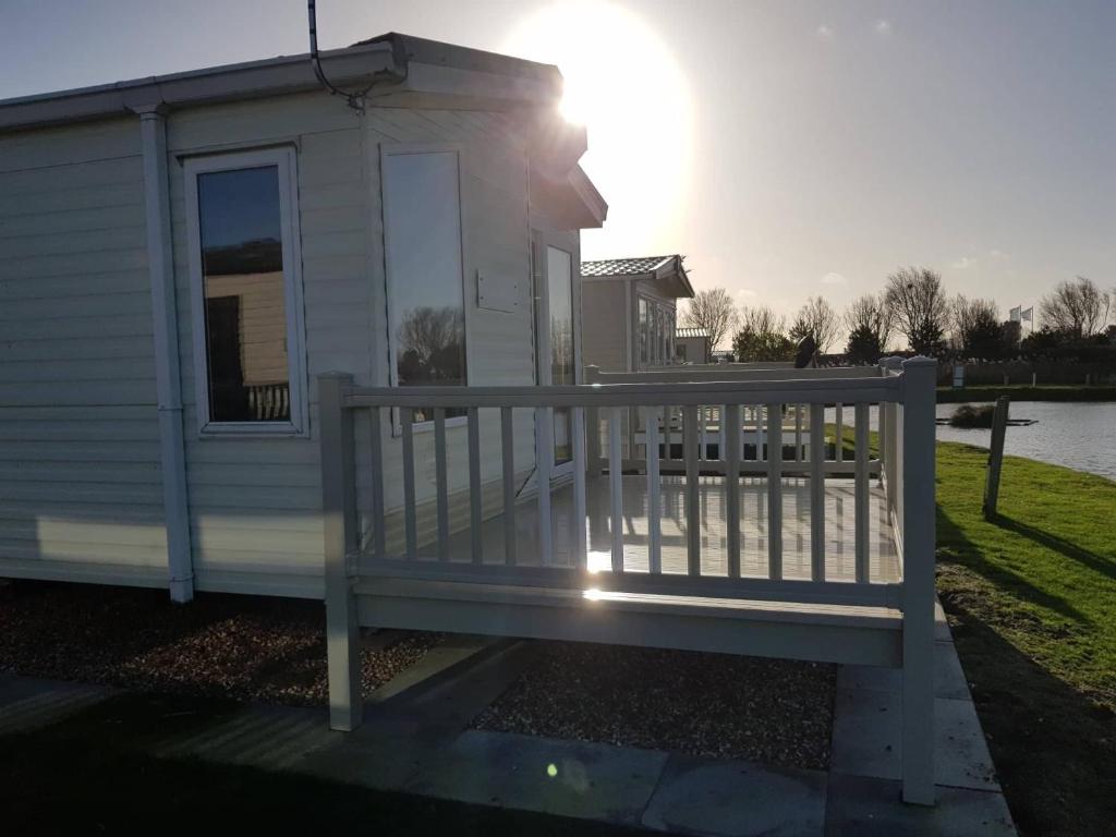 a house with a deck with the sun in the background at 8 BERTH DELUXE CARAVAN ML88 GOLDEN PALM CHAPEL ST LEONARDs in Chapel Saint Leonards