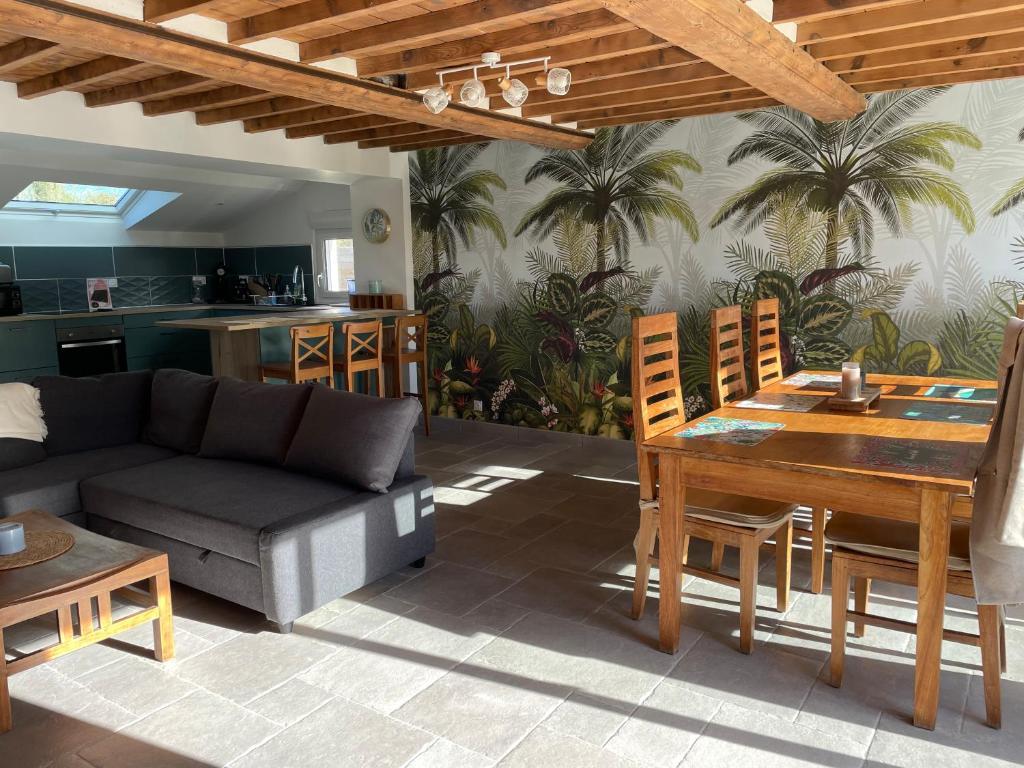 een woonkamer met een bank en een tafel en stoelen bij Charmante maison à deux pas de la mer in Gouville-sur-Mer