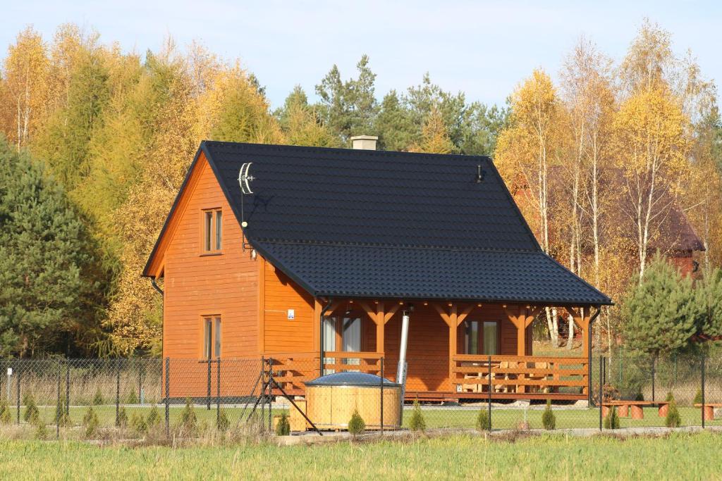 une grande cabane en bois avec un toit noir dans l'établissement Domek Pod Wierzbą, à Sikorzyno