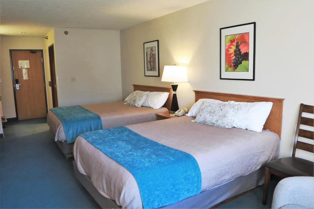um quarto de hotel com duas camas e uma cadeira em Heritage Inn em Wahoo