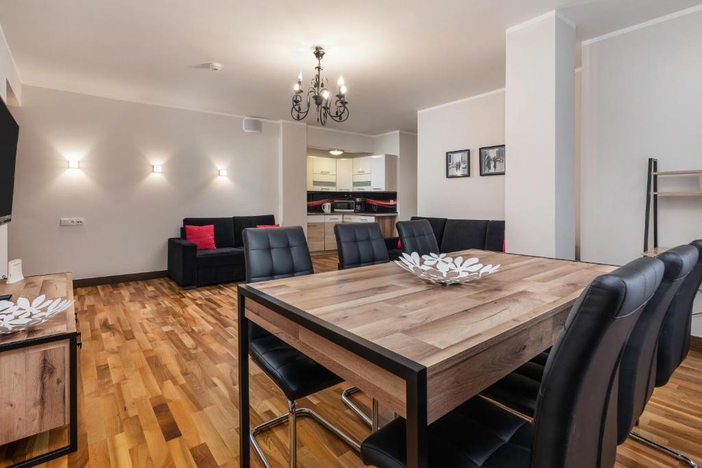 a dining room and living room with a wooden table and chairs at Jantar Apartamenty Deluxe Royal Tulip Sand Hotel in Kołobrzeg