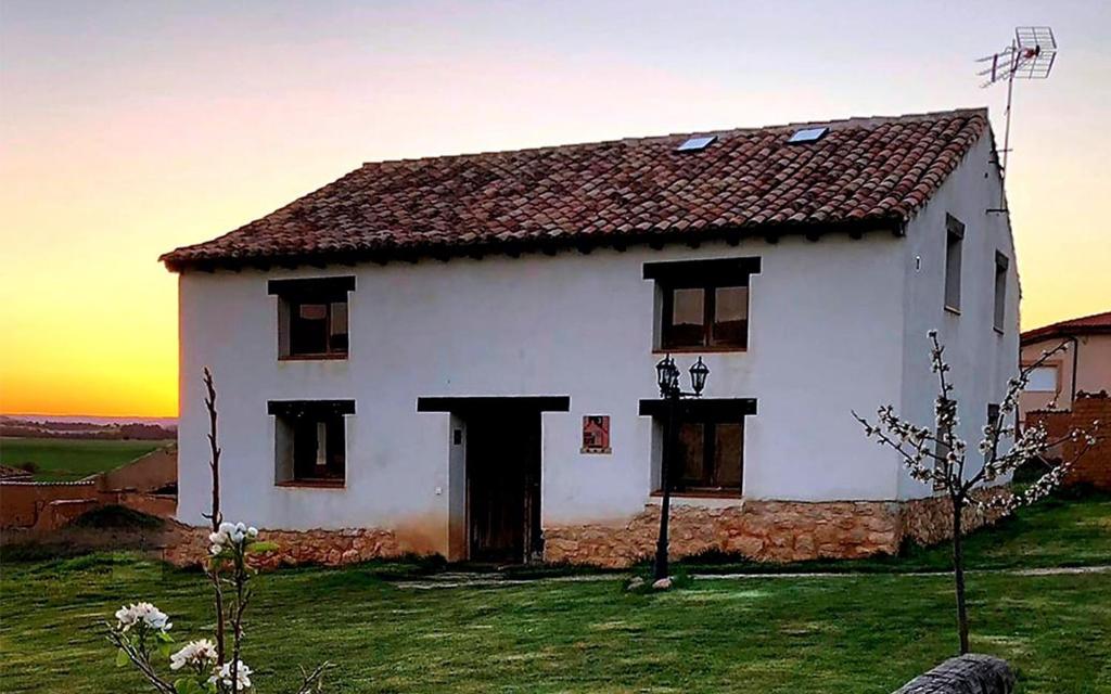 une grande maison blanche avec un coucher de soleil en arrière-plan dans l'établissement Tierras de Aguilera, à Aguilera