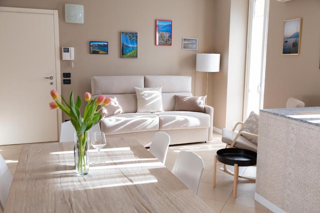 ein Wohnzimmer mit einem weißen Sofa und einem Tisch in der Unterkunft Bellagio Love apartment Pool Near lake Free parking in Bellagio