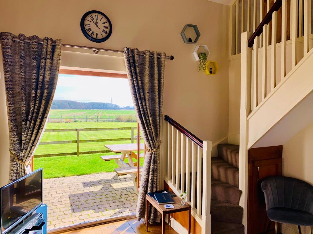 a living room with a staircase and a clock on the wall at Grange Farm Cottages in Wressell