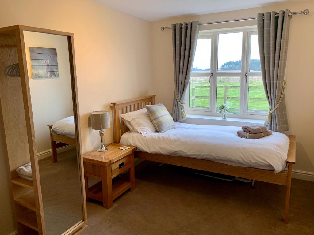 una camera da letto con un letto, uno specchio e una finestra di Grange Farm Cottages a Wressell