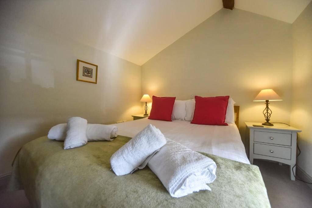 una camera da letto con un grande letto bianco con cuscini rossi di Church Farm Holiday Cottages - Winnets Cottage ad Ashbourne