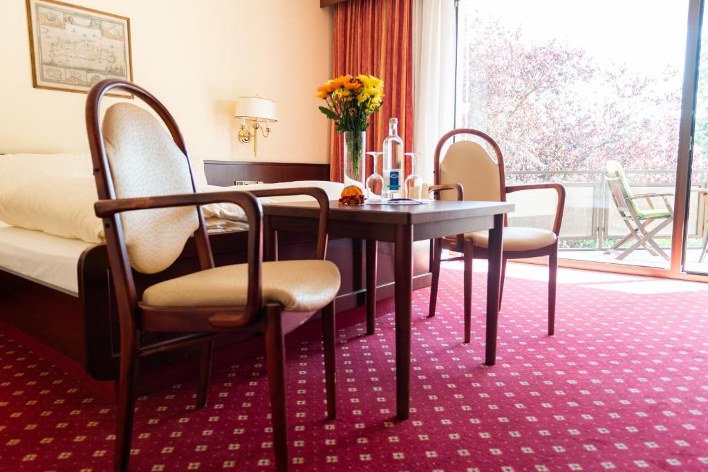 デュッセルドルフにあるホテル ハウス アム ズーのテーブル、椅子、ベッドが備わる客室です。