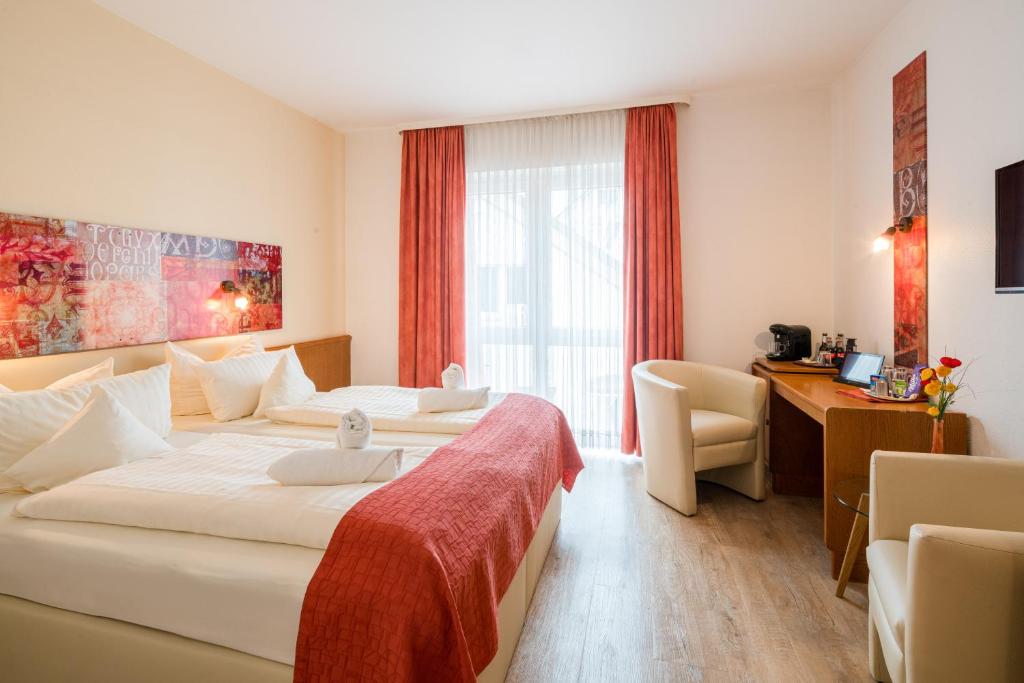 a hotel room with two beds and a desk at Arador-City Hotel in Bad Oeynhausen