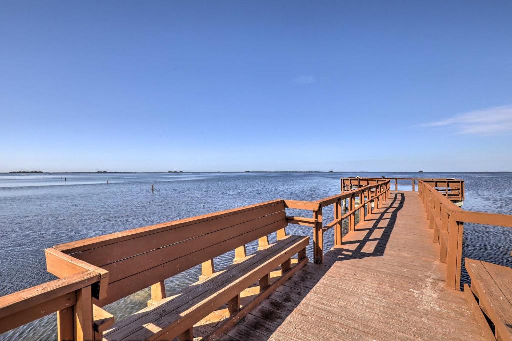 a wooden pier with benches on the water at Cozy Crystal Beach Cottage Walk to Shoreline in Crystal Beach