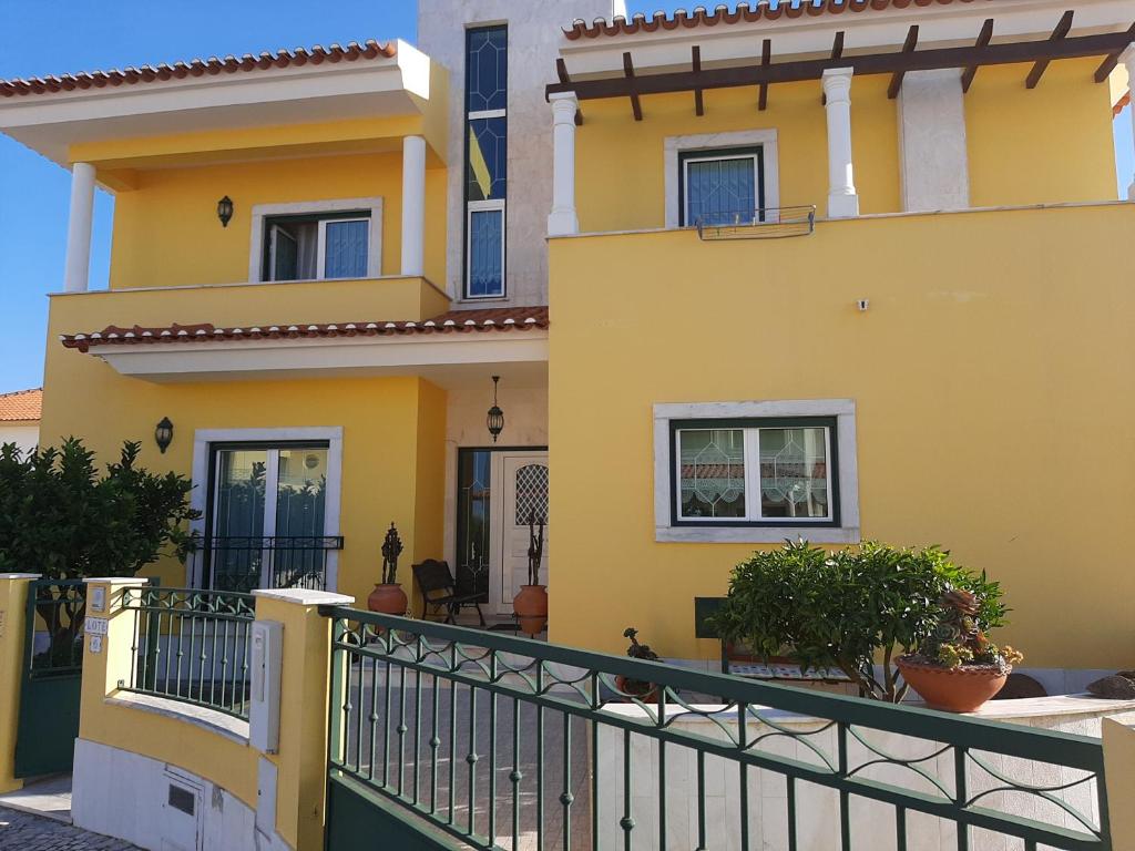 une maison jaune avec une clôture noire dans l'établissement MARIA INÊS HOUSE, à Nazaré