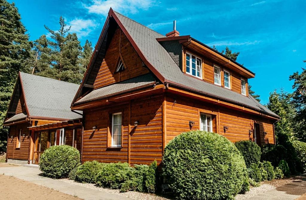 a large wooden house with a black roof at Leśny Zakątek Borkowo in Borkowo