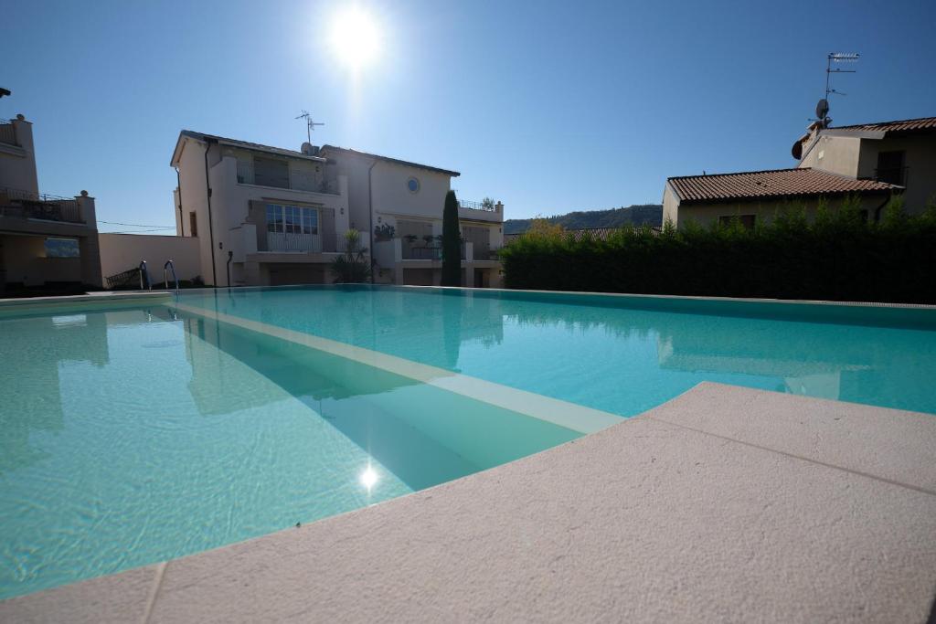een groot blauw zwembad voor een gebouw bij ApartmentsGarda - Corte dei Molini in Garda