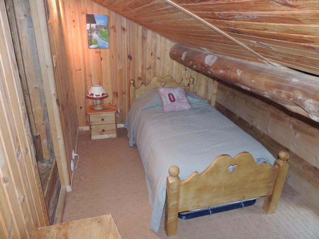 a small bedroom with a bed in a log cabin at La Bournerie in Le Grand-Bornand