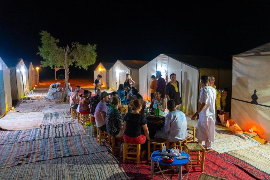 a group of people sitting in chairs in front of tents at Desert Camp Erg Chebbi in Merzouga