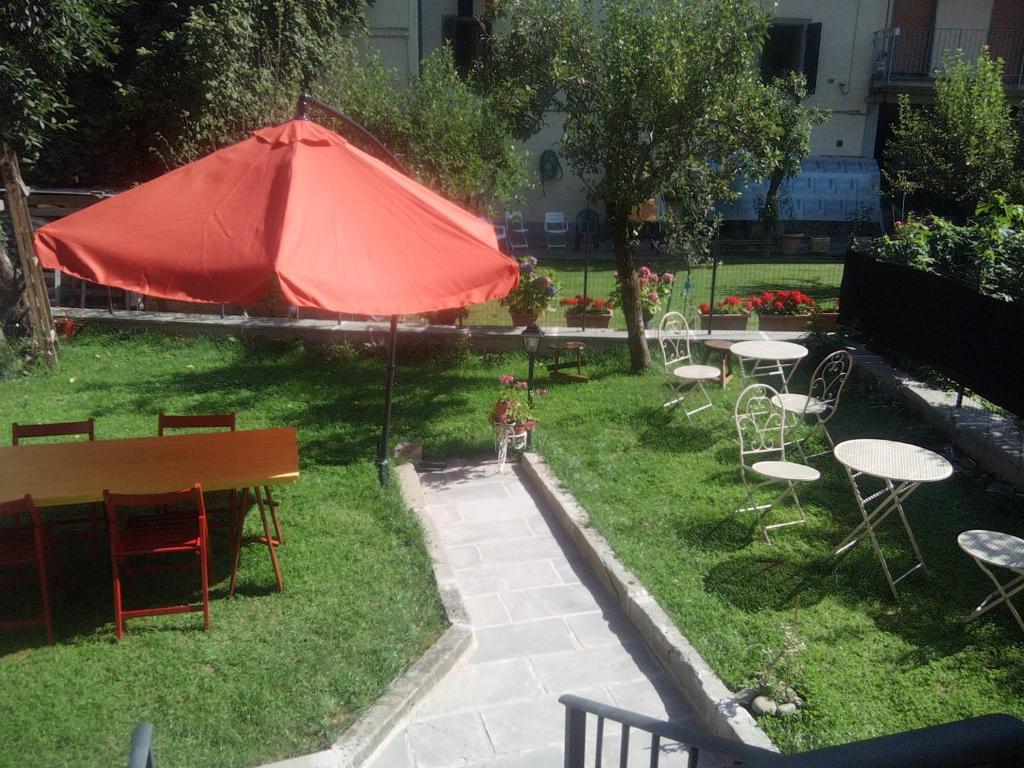 a garden with tables and chairs and a red umbrella at B&B Fiume Bianco in Fiumalbo