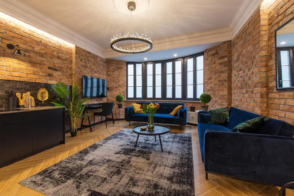 a living room with blue couches and a brick wall at Galeria Italiana Apartments in Wrocław