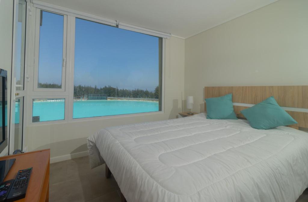 um quarto com uma cama grande e uma janela grande em Departamento con Laguna artificial en Las Cruces em Valparaíso