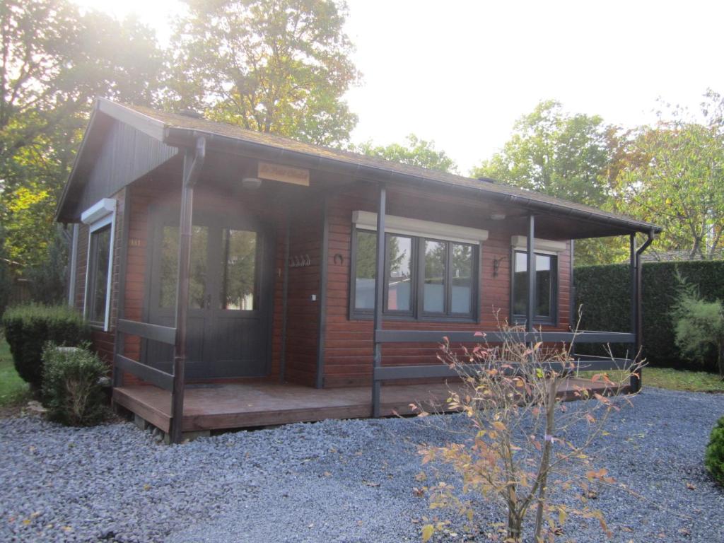 Cabaña de madera pequeña con porche y ventanas en Le Petit Chalet, en Resteigne