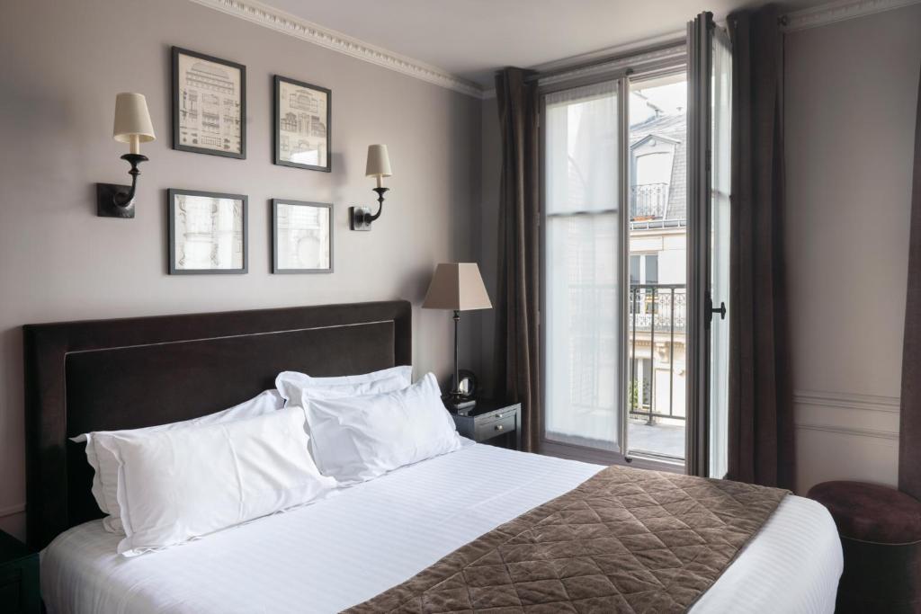 een slaapkamer met een bed met witte kussens en een raam bij Hotel Saint-Louis Pigalle in Parijs