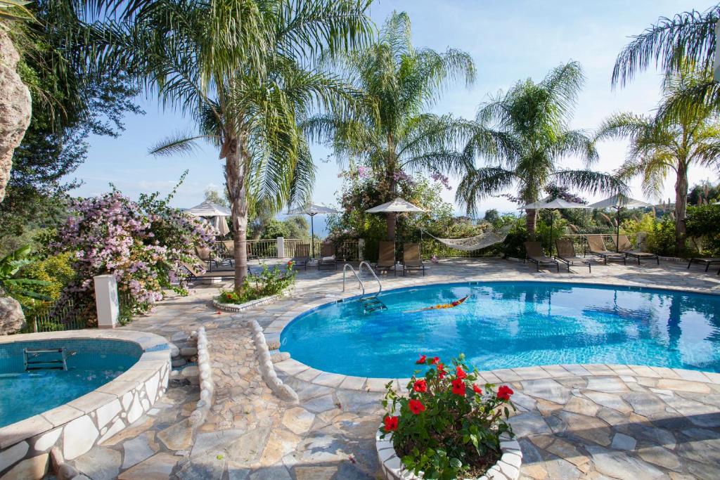 a swimming pool with palm trees and a resort at Filoxenia Sea View in Parga