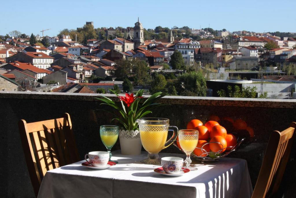 einen Tisch mit Orangen und Saft auf einem Balkon mit Aussicht in der Unterkunft Panoramic City View Apartment - Guimarães in Guimarães