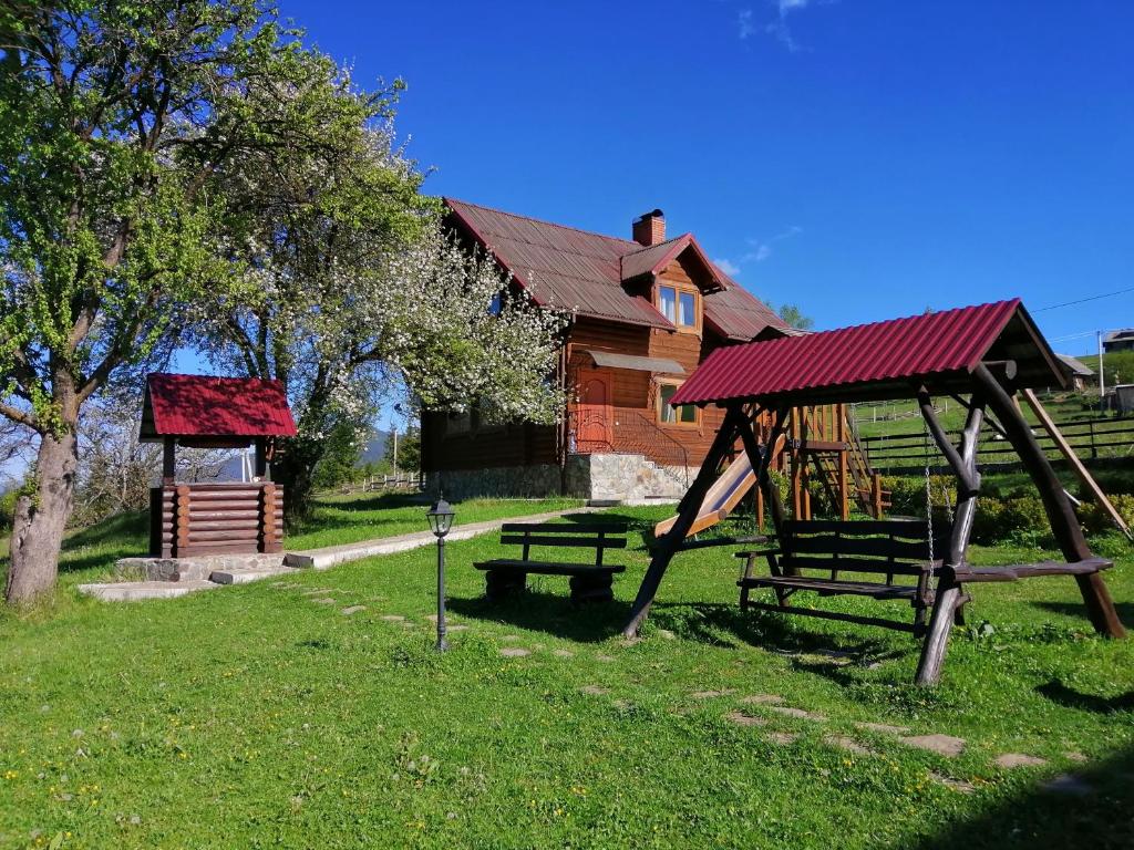 a park with a swing and a bench and a building at Polonyna in Verkhovyna